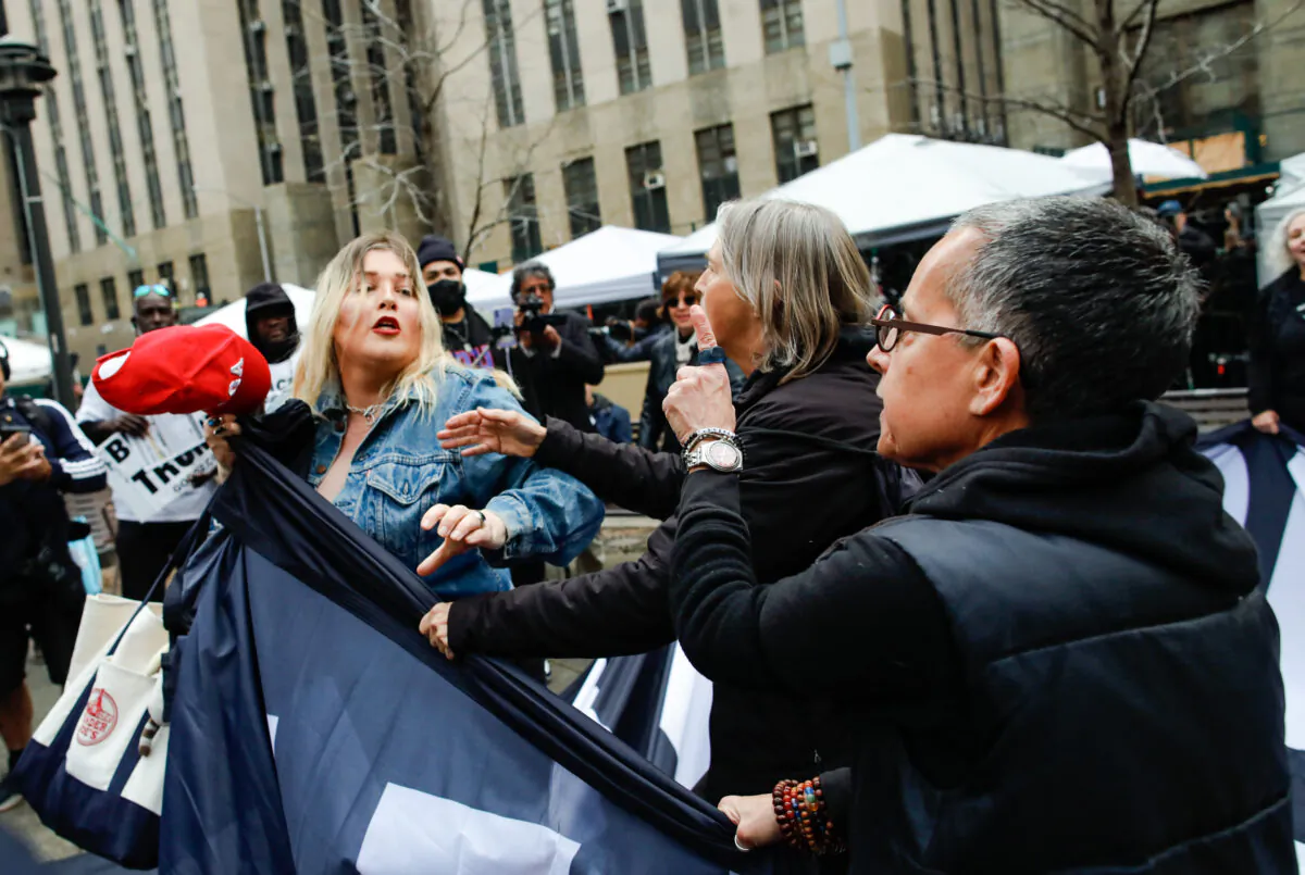 A Trump supporter (L) removes a banner from anti-Trump protesters outside the Manhattan Criminal Courthouse on April 4, 2023 in New York City. (Kena Betancur/Getty Images)