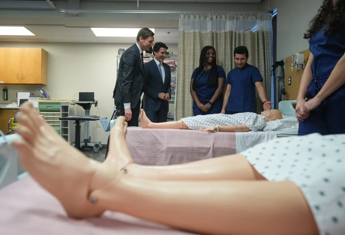 B.C. Premier David Eby (L), and Prime Minister Justin Trudeau talk with psychiatric nursing students Derin Omojokun (3rd L), and Abdul Amarkhil (R), at Kwantlen Polytechnic University, in Langley, B.C., on March 1, 2023. 