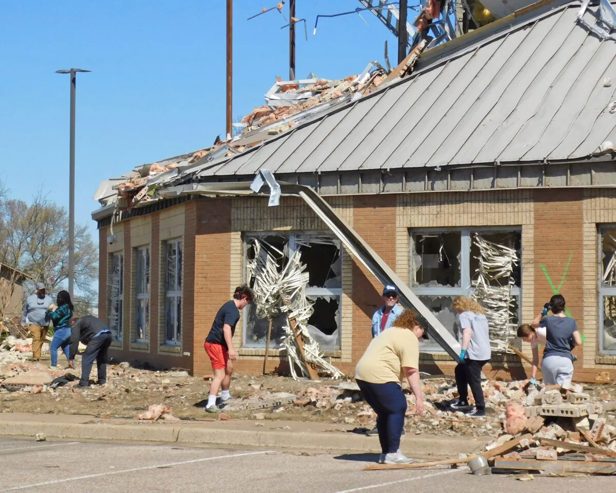 Following severe weather the previous night, volunteers clean up at Wynne High School near the front entrance of the school on E. Jackson Avenue in Wynne, Ark., on April 1, 2023. (Nena Zimmer/The Jonesboro Sun via AP)