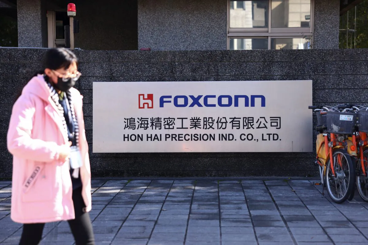 A woman walks past the logo of Foxconn outside a company's building in New Taipe City, Taiwan, on Dec. 22, 2022. (Annabelle Chih/Reuters)