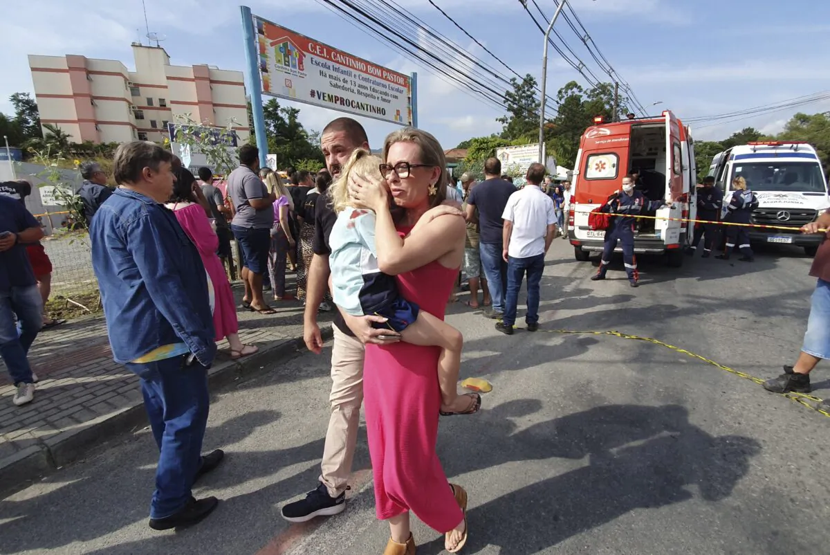 A woman conforts a crying girl outside the daycare center "Cantinho do Bom Pastor" after a fatal attack on children in Blumenau, Santa Catarina state, Brazil, on April 5, 2023. (Patrick Rodrigues/Portal NSC Total via AP)