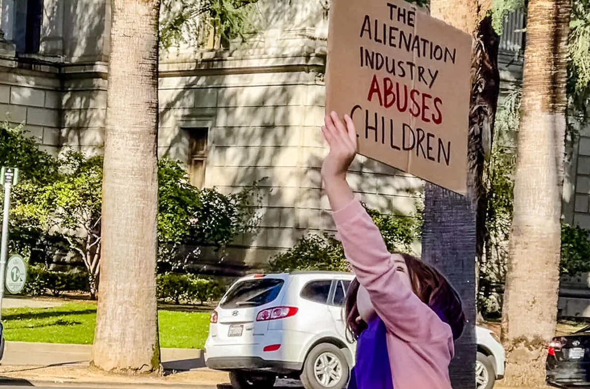 A child holds a sign outside of a courthouse as part of a protest against court-ordered reunification therapy. (Courtesy of Alienation Industry)