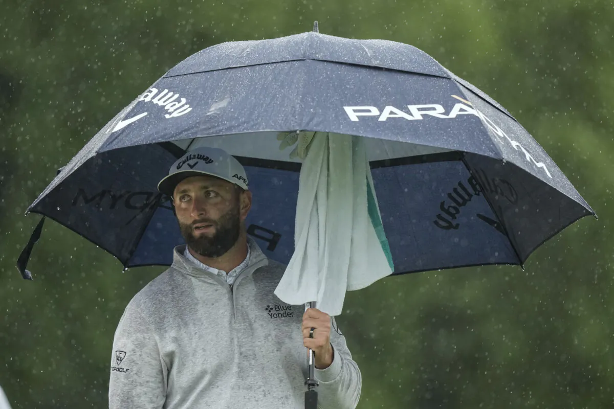 Jon Rahm, of Spain, waits to play in the rain on the 18th hole during the weather delayed second round of the Masters golf tournament at Augusta National Golf Club, in Augusta, GA on April 8, 2023. (Charlie Riedel/AP Photo)