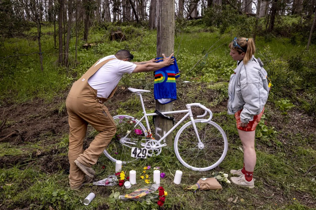 Sydney Parcell (R) and Wagner Sousa place a track cycling world champion jersey at a memorial, near where friend Ethan Boyes was fatally struck by a vehicle earlier in the week, in San Francisco, on April 6, 2023. (Stephen Lam/San Francisco Chronicle via AP)