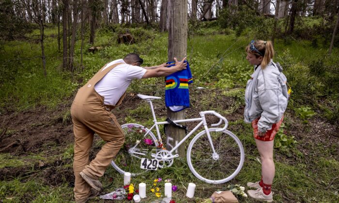 Sydney Parcell (R) and Wagner Sousa place a track cycling world champion jersey at a memorial, near where friend Ethan Boyes was fatally struck by a vehicle earlier in the week, in San Francisco, on April 6, 2023. (Stephen Lam/San Francisco Chronicle via AP)