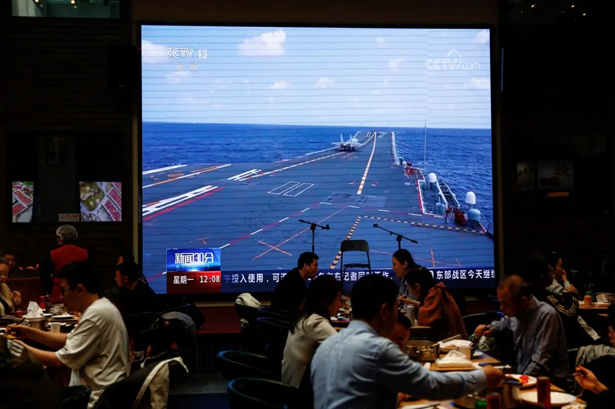 Customers dine near a giant screen broadcasting news footage of aircraft under the Eastern Theater Command of the Chinese military taking part in a combat readiness patrol and "Joint Sword" exercises around Taiwan, at a restaurant in Beijing on April 10, 2023. (Tingshu Wang/Reuters)