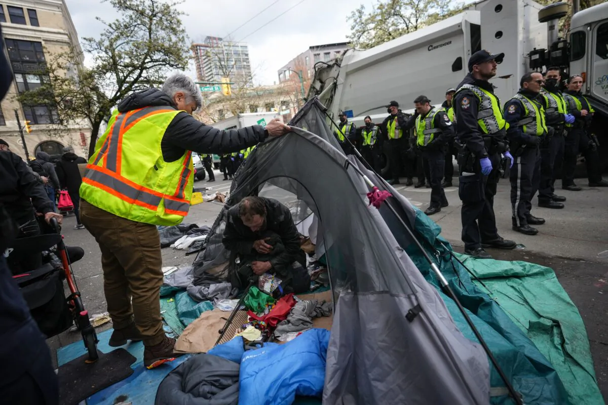 Police stand by while city workers clear an encampment on East Hastings Street in the Downtown Eastside of Vancouver on April 5, 2023. (The Canadian Press/Darryl Dyck)