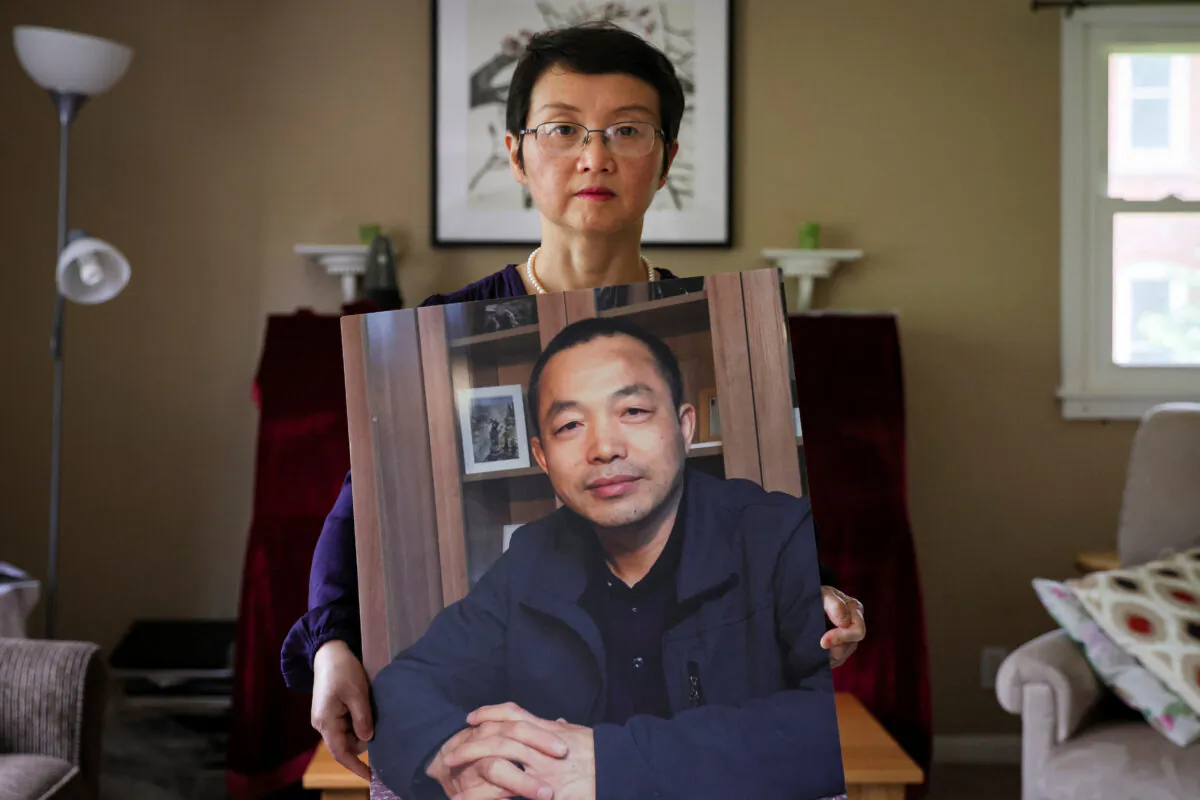 Sophie Luo Shengchun, the wife of jailed Chinese human rights lawyer, Ding Jiaxi, poses with a photo of him at her home in Alfred, New York, on July 28, 2022. (Brendan McDermid/Reuters)