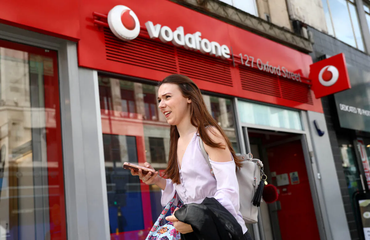 A woman holds a phone as she passes a Vodafone store in London on May 16, 2017. (Neil Hall/Reuters)