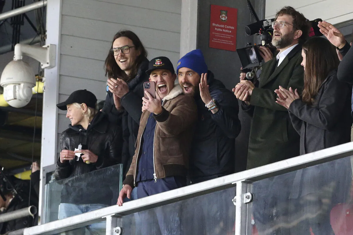Wrexham owners Ryan Reynolds (center L) and Rob McElhenney (center R) react during the National League match between Wrexham and Notts County at the Racecourse Ground in Wrexham, Wales, on April 10, 2023. (Barrington Coombs/PA via AP)