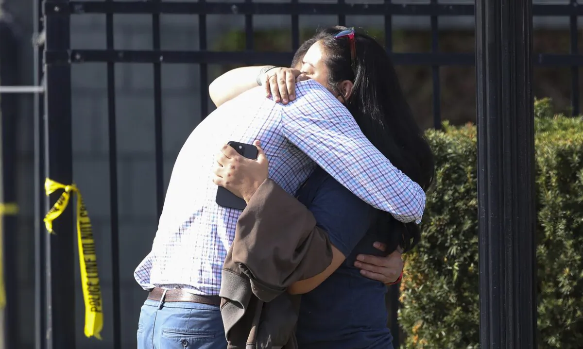 Two people embrace outside of a building where a shooting took place in Louisville, Ky., on April 10, 2023. (Michael Clevenger/Courier Journal via AP)