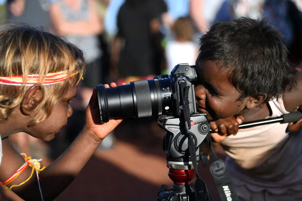 Indigenous Anangu children play with a camera during a ceremony marking the permanent ban on climbing Uluru, also known as Ayers Rock, at Uluru-Kata Tjuta National Park in Australia's Northern Territory on Oct. 27, 2019. (Saeed Khan/AFP via Getty Images)