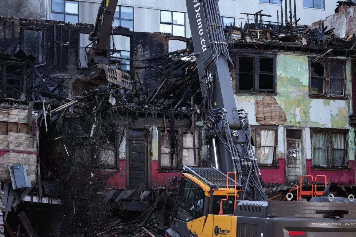 Debris falls to the ground as demolition resumes on the Winters Hotel after a body was found in the single room occupancy (SRO) building, in Vancouver, B.C., on April 22, 2022. (The Canadian Press/Darryl Dyck)