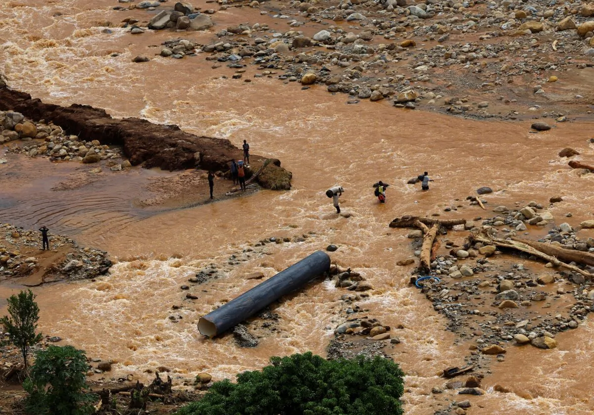 People cross a flooded area in Muloza on the border with Mozambique after the aftermath of Tropical Cyclone Freddy, around 100 kilometers outside Blantyre, Malawi, on March 18, 2023. (Esa Alexander/Reuters)