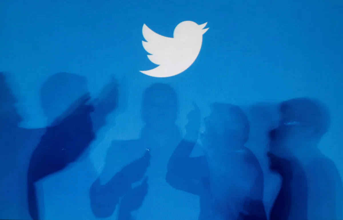The shadows of people holding mobile phones are cast onto a backdrop projected with the Twitter logo in an illustration picture taken in Warsaw, Poland, on Sept. 27, 2013. (Kacper Pempel/Reuters)