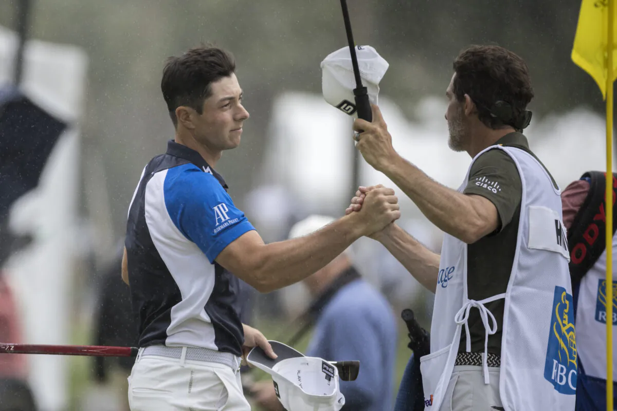 Viktor Holland, left, of Norway, shakes hands with his caddie on the ninth green during the first round of the RBC Heritage golf tournament, in Hilton Head Island, S.C., April 13, 2023. (Stephen B. Morton/AP Photo)