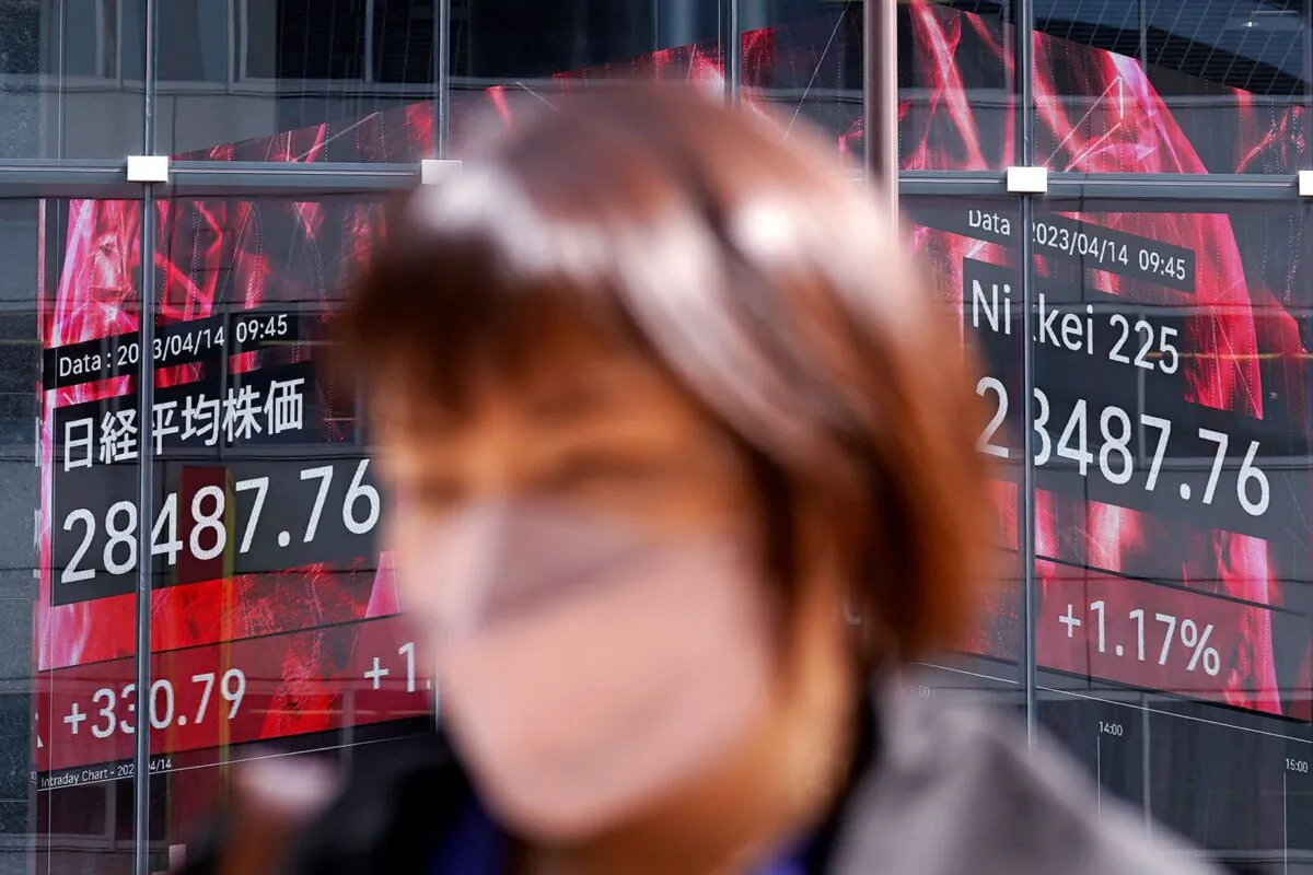A person walks near an electronic stock board showing Japan's Nikkei 225 index in Tokyo on April 14, 2023. (Eugene Hoshiko/AP Photo)