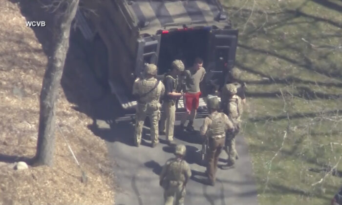 Jack Teixeira, in T-shirt and shorts, being taken into custody by armed tactical agents in Dighton, Mass., on April 13, 2023. (WCVB-TV via AP)