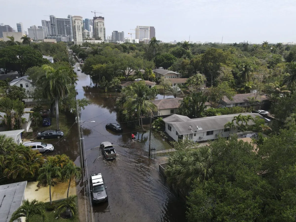 Trucks and a resident on foot make their way through receding floodwaters in the Sailboat Bend neighborhood of Fort Lauderdale, Fla., on April 13, 2023. (Rebecca Blackwell/AP Photo)