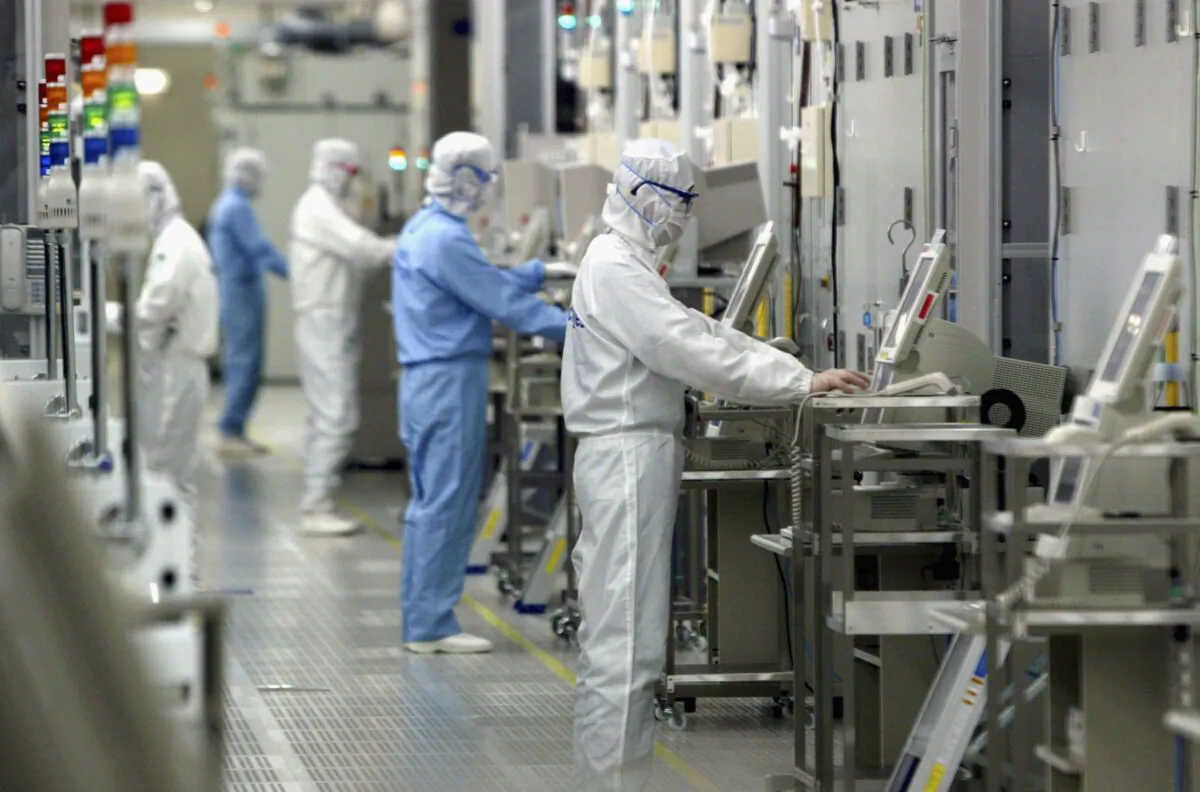 Technicians at work in the clean room of the Fab Equipment at a semiconductor company, Renesas Technology Corp., in Ibaraki, Japan, on June 17, 2004. (Koichi Kamoshida/Getty Images)