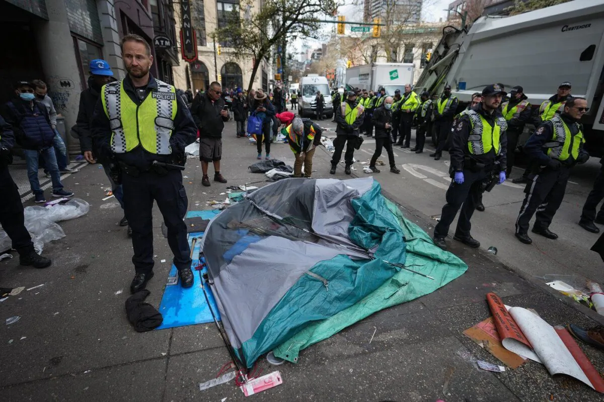 Vancouver police officers surround a tent with a person still inside as city workers clear an encampment on East Hastings Street in the Downtown Eastside of Vancouver, B.C., April 5, 2023. (The Canadian Press/Darryl Dyck)
