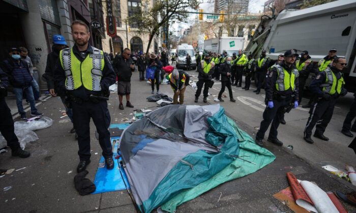 Vancouver police officers surround a tent with a person still inside as city workers clear an encampment on East Hastings Street in the Downtown Eastside of Vancouver, B.C., April 5, 2023. (The Canadian Press/Darryl Dyck)
