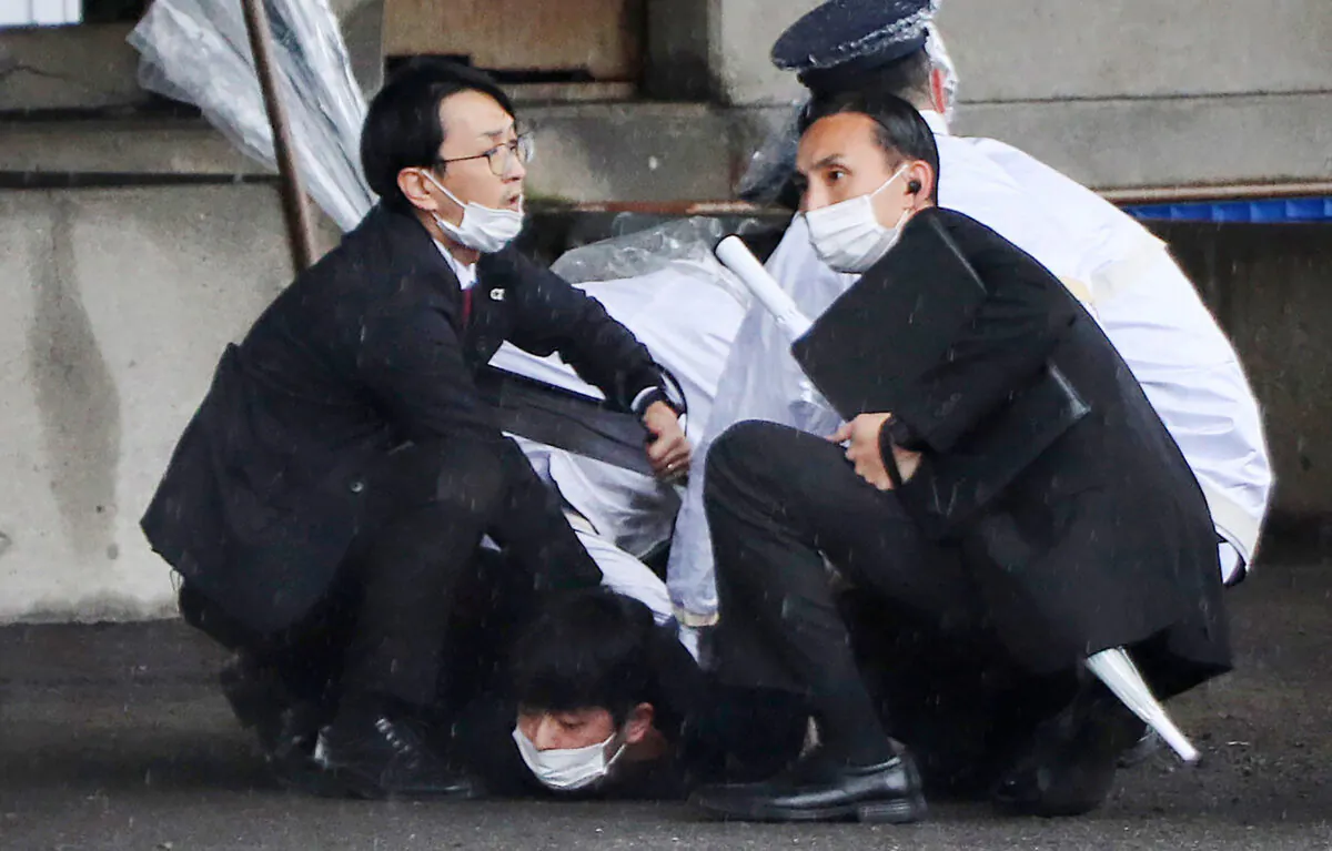 A man (bottom) is detained after throwing an apparent "smoke bomb" in Wakayama, Japan, on April 15, 2023, where Japan's Prime Minister was due to give a speech. (STR/JIJI Press/AFP via Getty Images)