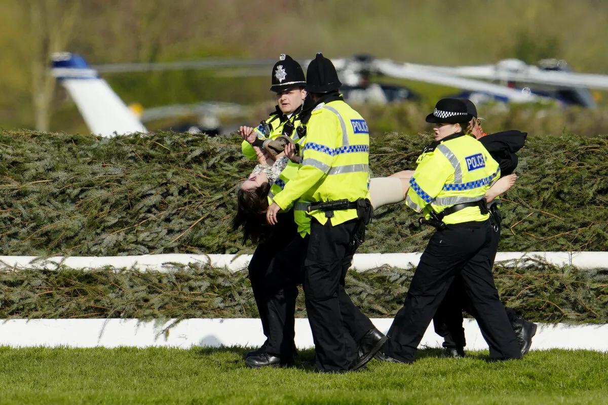 Members of the police forces remove a protester before the start of the Grand National horse race at Aintree Racecourse in Liverpool, England, on April 15, 2023. (Jon Super/AP Photo)