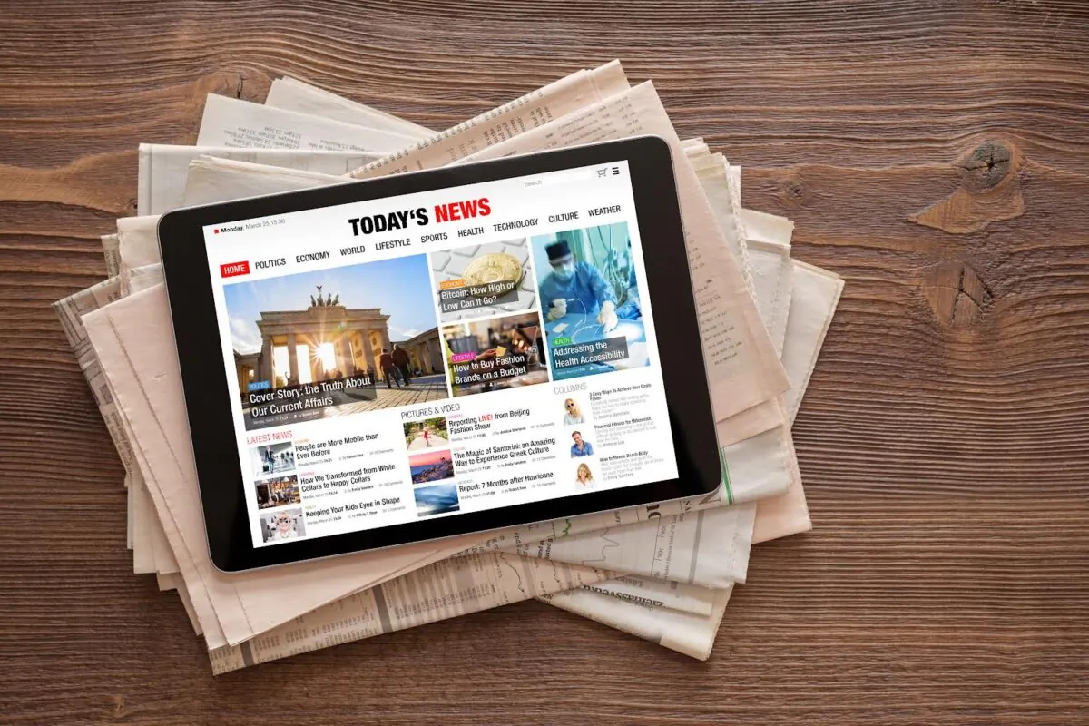 A tablet with a generic news website on stack of newspapers. (Kaspars Grinvalds/Shutterstock)