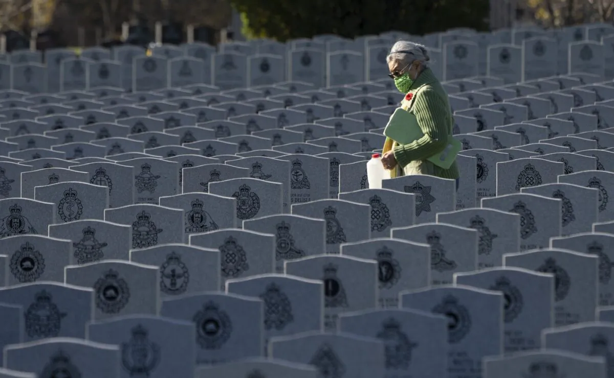 A woman walks among the rows of Canadian soldier's grave stones at the National Military Cemetery in Ottawa on Nov. 10, 2021. (The Canadian PressAdrian Wyld)