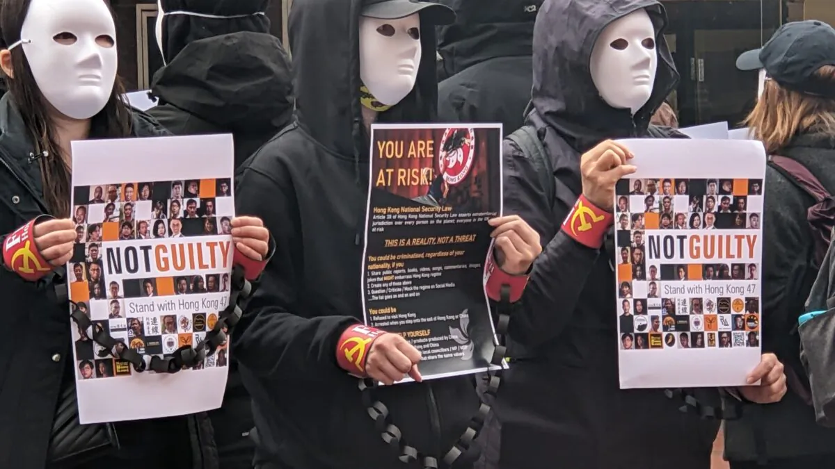 On April 15, 2023, Hongkongers in Reading, UK, attended a Silent Stand with Hong Kong global campaign. Participants wore white masks with awareness posters, while others were handcuffed with props. (Shan Lam/The Epoch Times)