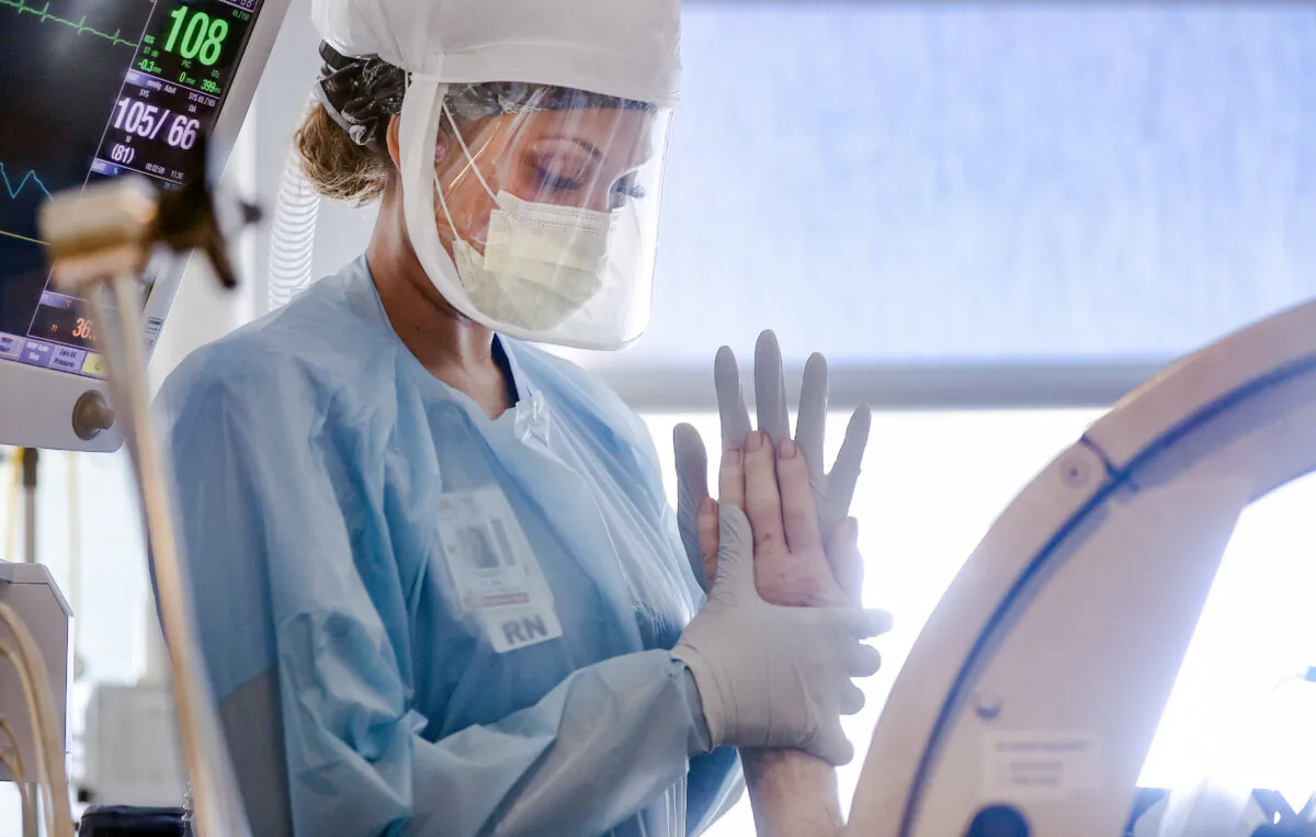 A nurse wears personal protective equipment (PPE) as she performs range of motion exercises on a COVID-19 patient. (Mario Tama/Getty Images)
