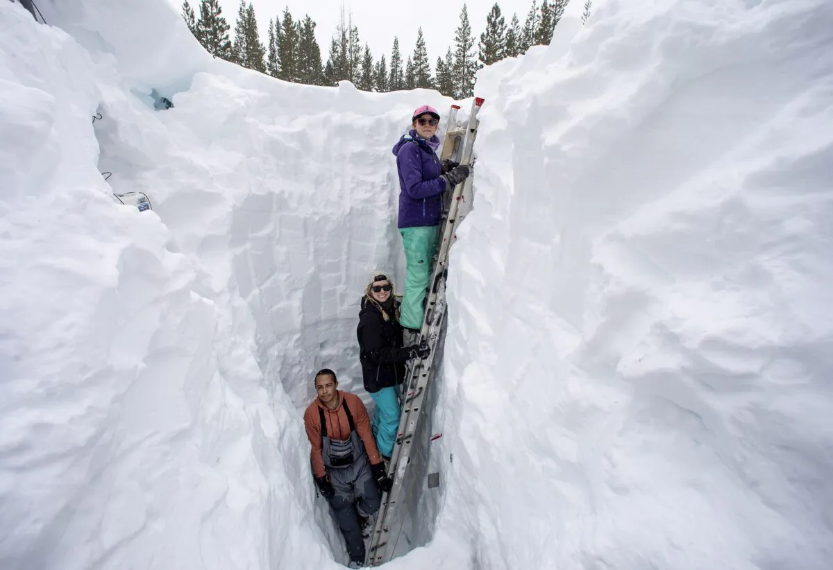 Working inside a nearly 18-foot-deep snow pit at the UC Berkeley Central Sierra Snow Lab, (L–R) Shaun Joseph, Claudia Norman, Helena Middleton take measurements of snow temperatures ahead of a weather storm in Soda Springs, Calif., on March 9, 2023. (Karl Mondon/Bay Area News Group via AP)