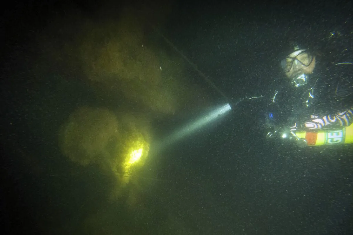 Diver Steve Abbate inspecting a propeller on April 16, 2023, of the 92-foot attack submarine Defender that was scuttled by the Army Corp of Engineers in 1946. (Joe Mazraani/Shoreline Diving Services via AP)
