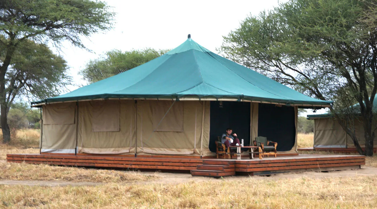A guest warms up with complimentary tea on the veranda of his tent at the Honeyguide Tarangire Camp in Tanzania. (Colleen Thomas/TNS)