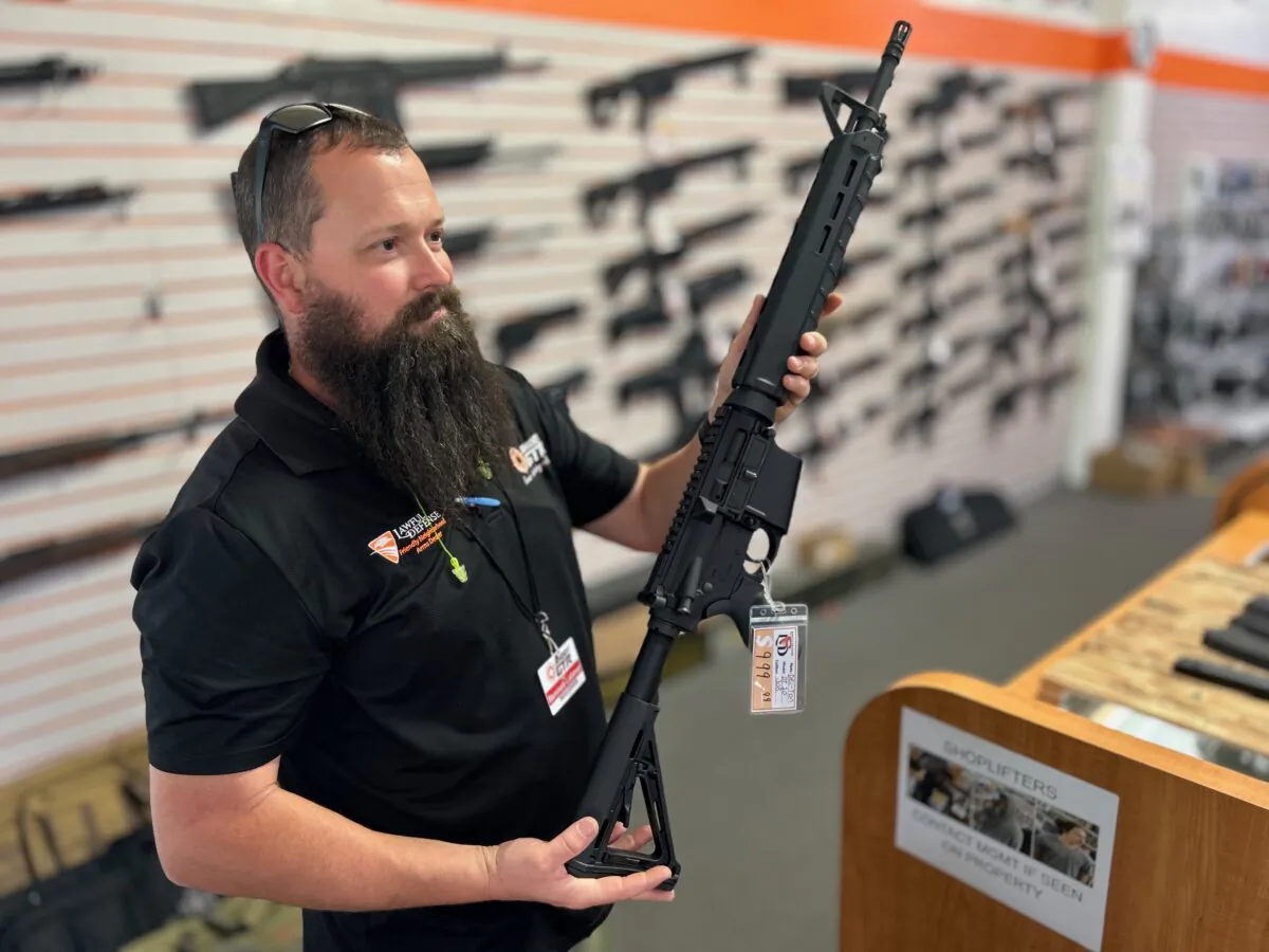 A gun store employee shows a customer an AR-style weapon at Lawful Defense in Gainesville, Fla., on April 19, 2023. AR stands for the ArmaLite rifle brand and the guns styled like it, and not "assault rifle," as commonly believed. (Nanette Holt/The Epoch Times)