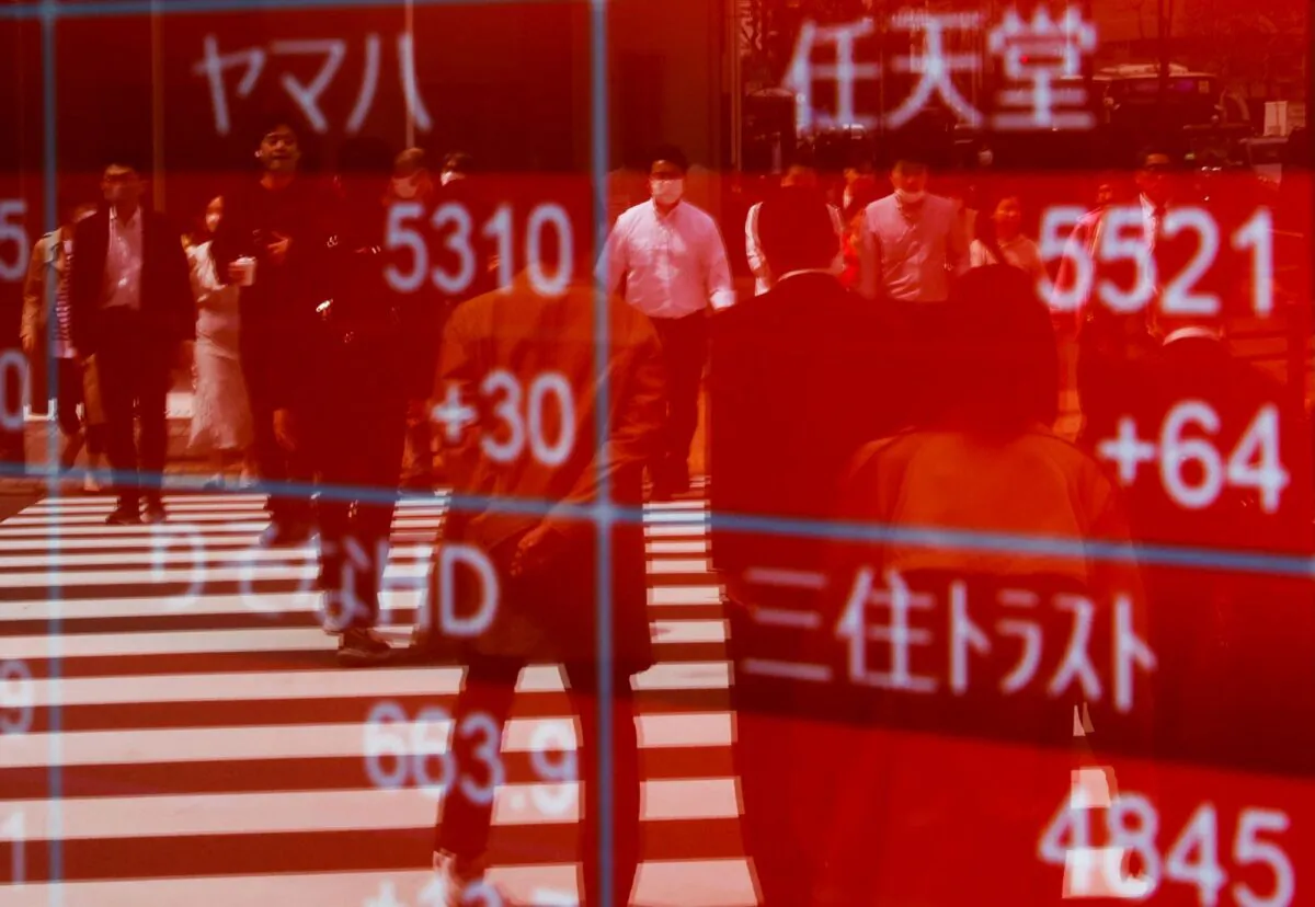 Passersby are reflected on an electric stock quotation board outside a brokerage in Tokyo, Japan, on April 18, 2023. (Issei Kato/Reuters)
