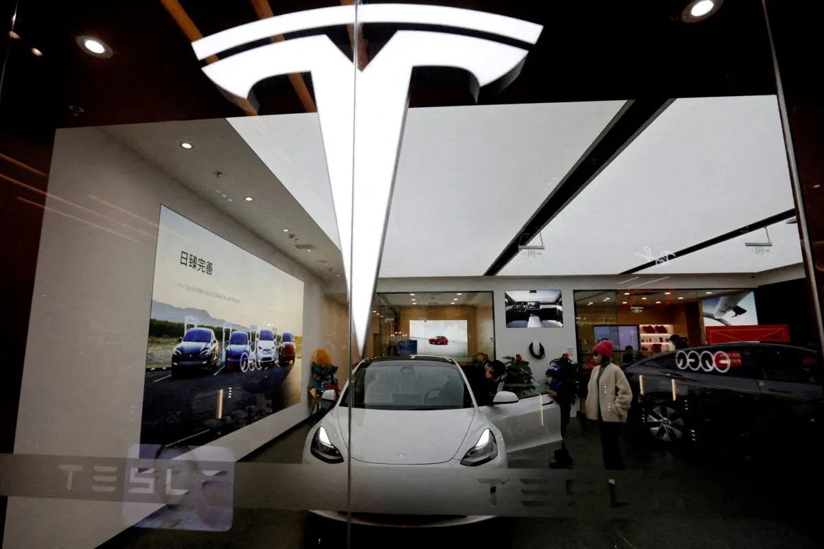 Visitors check a Tesla Model 3 car next to a Model Y displayed at a showroom of the electric vehicle (EV) maker in Beijing on Feb. 4, 2023. (Florence Lo/Reuters)