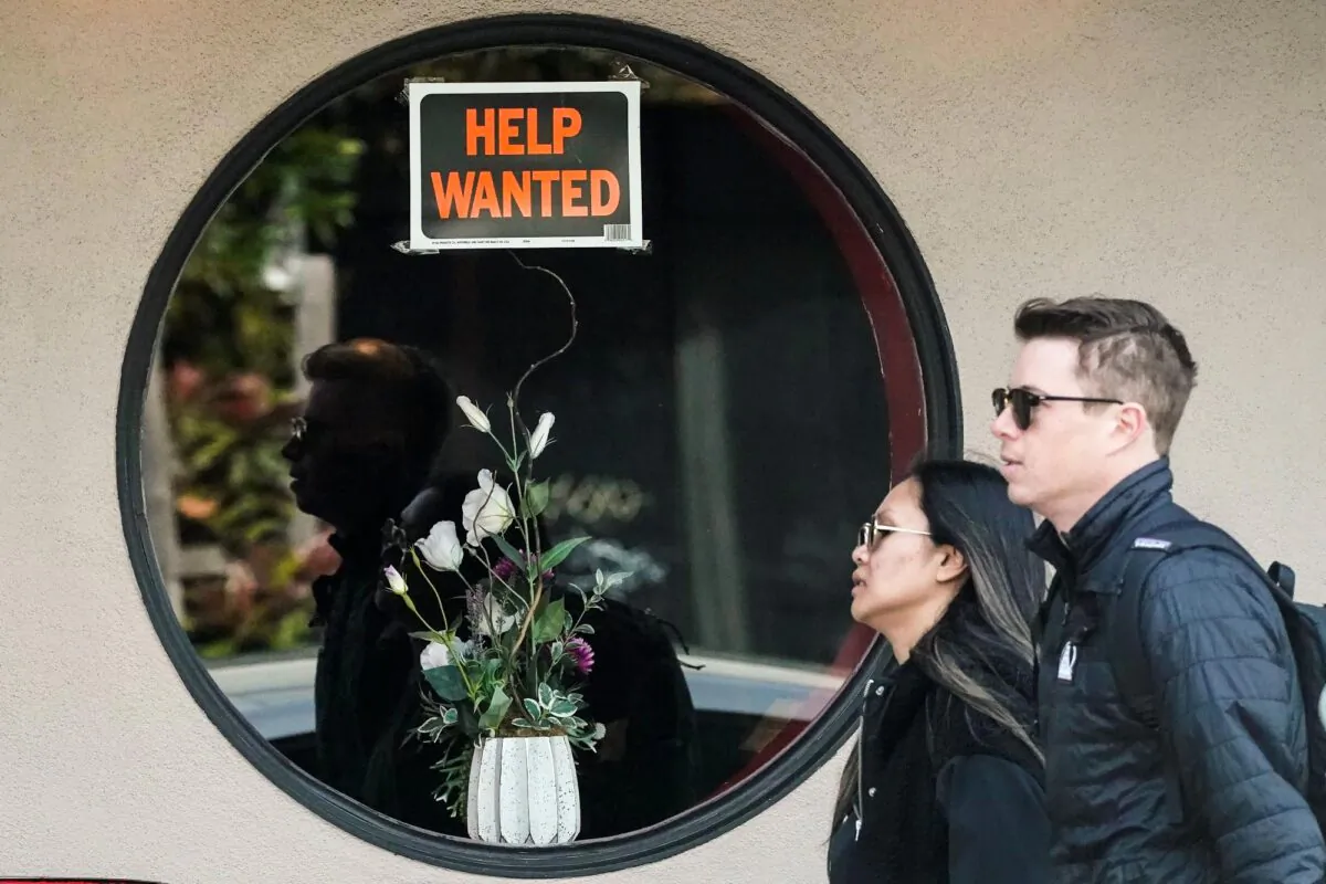 Pedestrians walk past a help wanted sign posted on the door of a restaurant in San Francisco, Calif., on April 18, 2023. (Jeff Chiu/AP Photo)