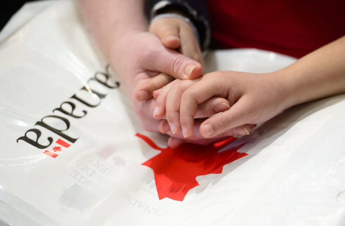 A mother holds the hands of her daughter as they become new Canadians and take the Oath of Citizenship on Parliament Hill in Ottawa on April 17, 2019. (Sean Kilpatrick/The Canadian Press)