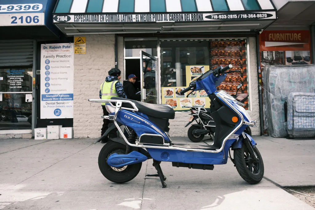 An electric scooter with a battery sits parked outside of a Bronx supermarket in New York City on March 6, 2023, the day after a 5-alarm fire tore through a market that fire officials are blaming on a faulty lithium-ion battery. (Spencer Platt/Getty Images)