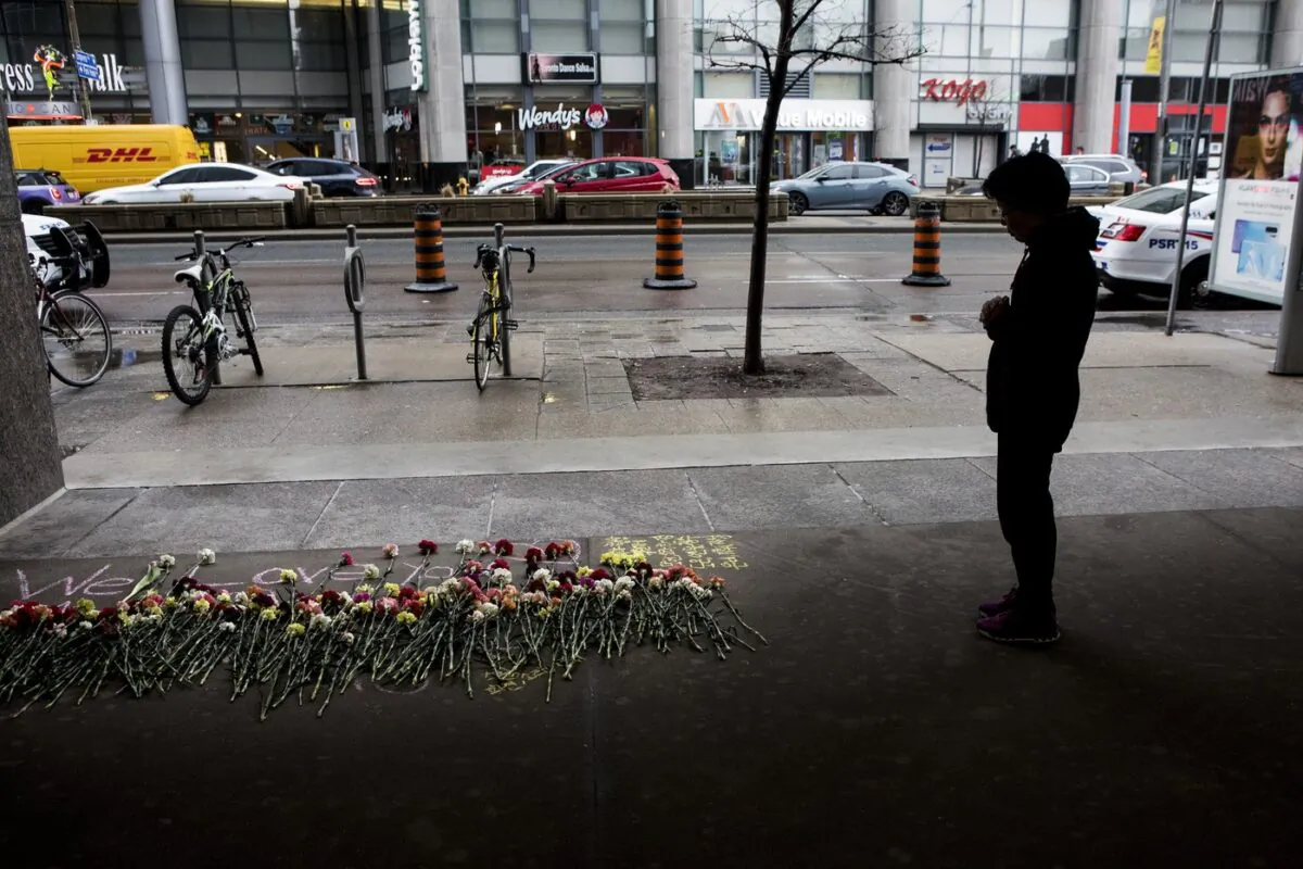 A woman stops to pay her respects at a makeshift memorial to one of the victims of a 2018 van attack, ahead of a vigil being held at Toronto's Mel Lastman Square, on April 23, 2019. (The Canadian Press/Chris Young)