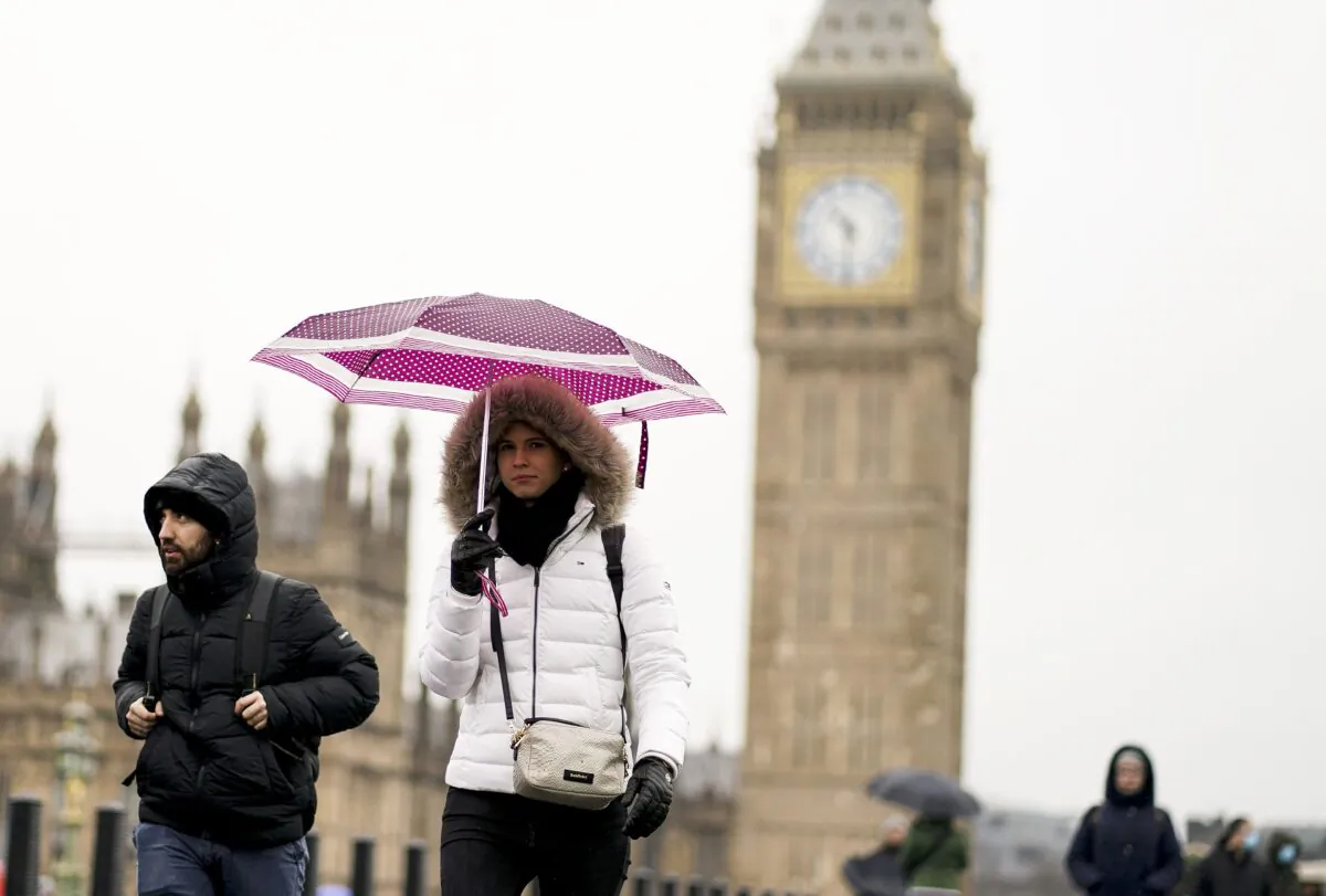 Members of the public shelter from the rain under umbrellas on Westminster Bridge in London, on March 9, 2023. (Jordan Pettitt/PA Media)