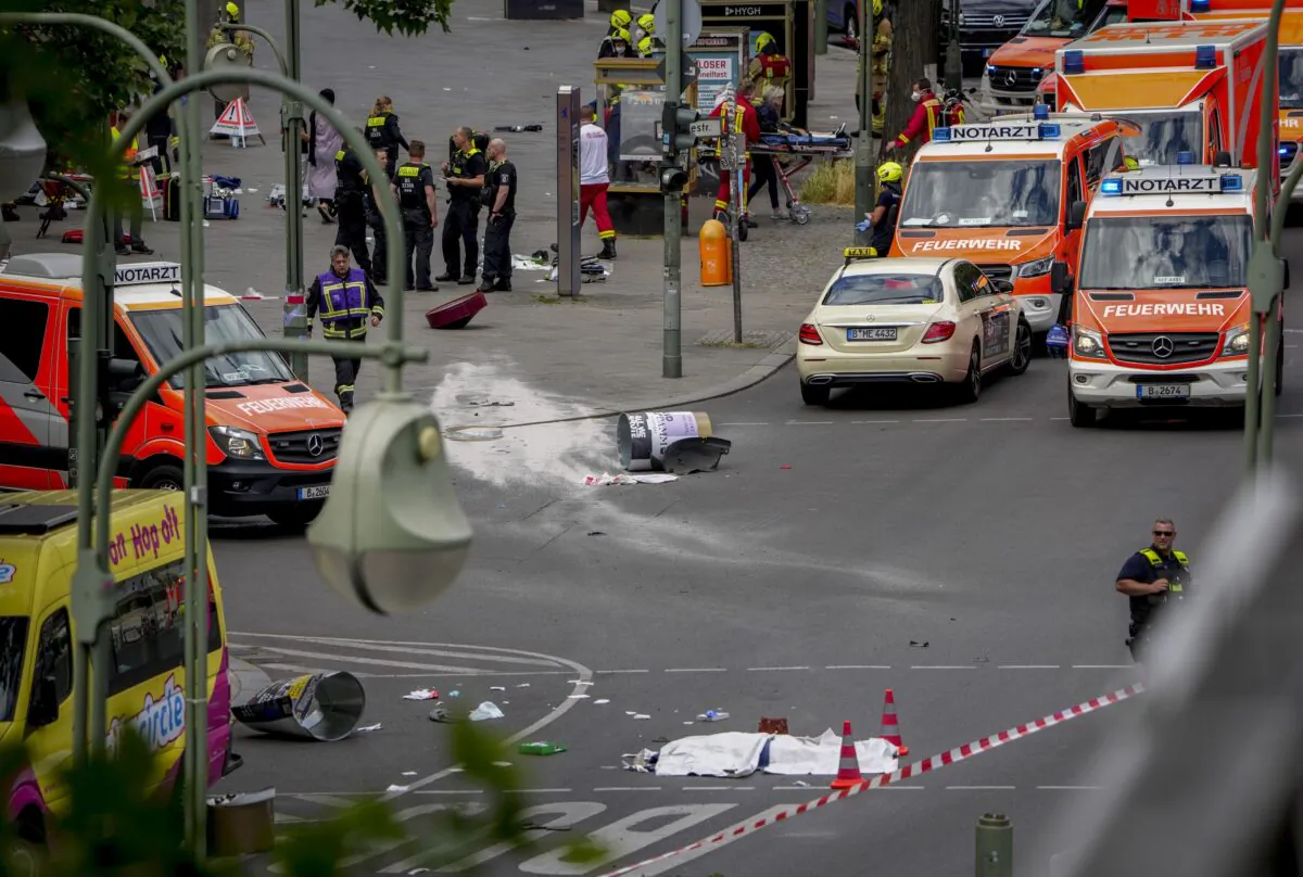 A covered body, foreground, lies on the street after a car crashed into a crowd of people in central Berlin on June 8, 2022. (Michael Sohn/AP Photo)