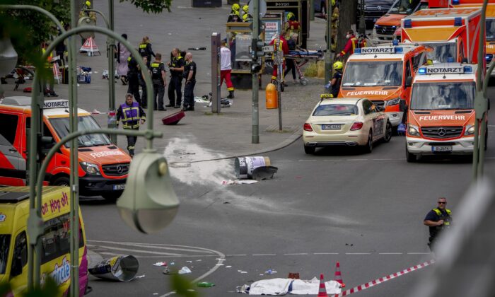 A covered body, foreground, lies on the street after a car crashed into a crowd of people in central Berlin on June 8, 2022. (Michael Sohn/AP Photo)