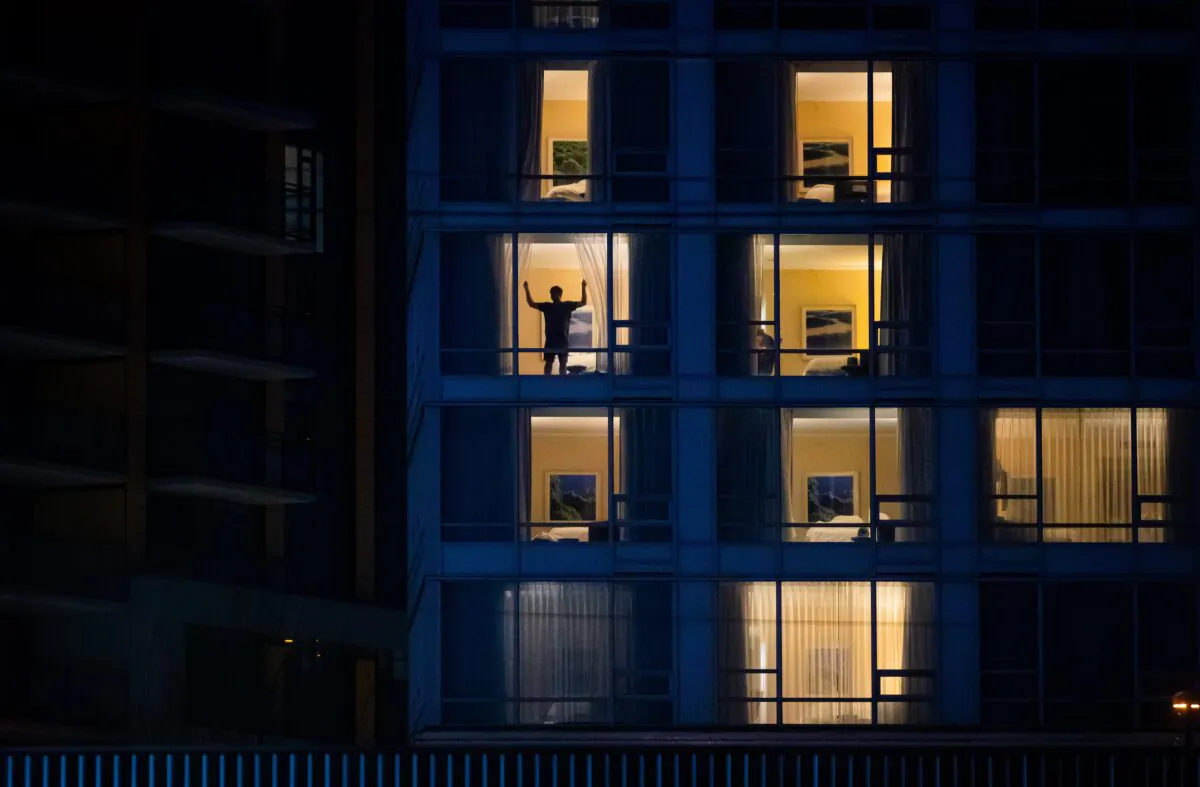A person closes the curtains in a room at a government-authorized COVID-19 quarantine hotel in Richmond, B.C., on Feb. 28, 2021. (Darryl Dyck/The Canadian Press)