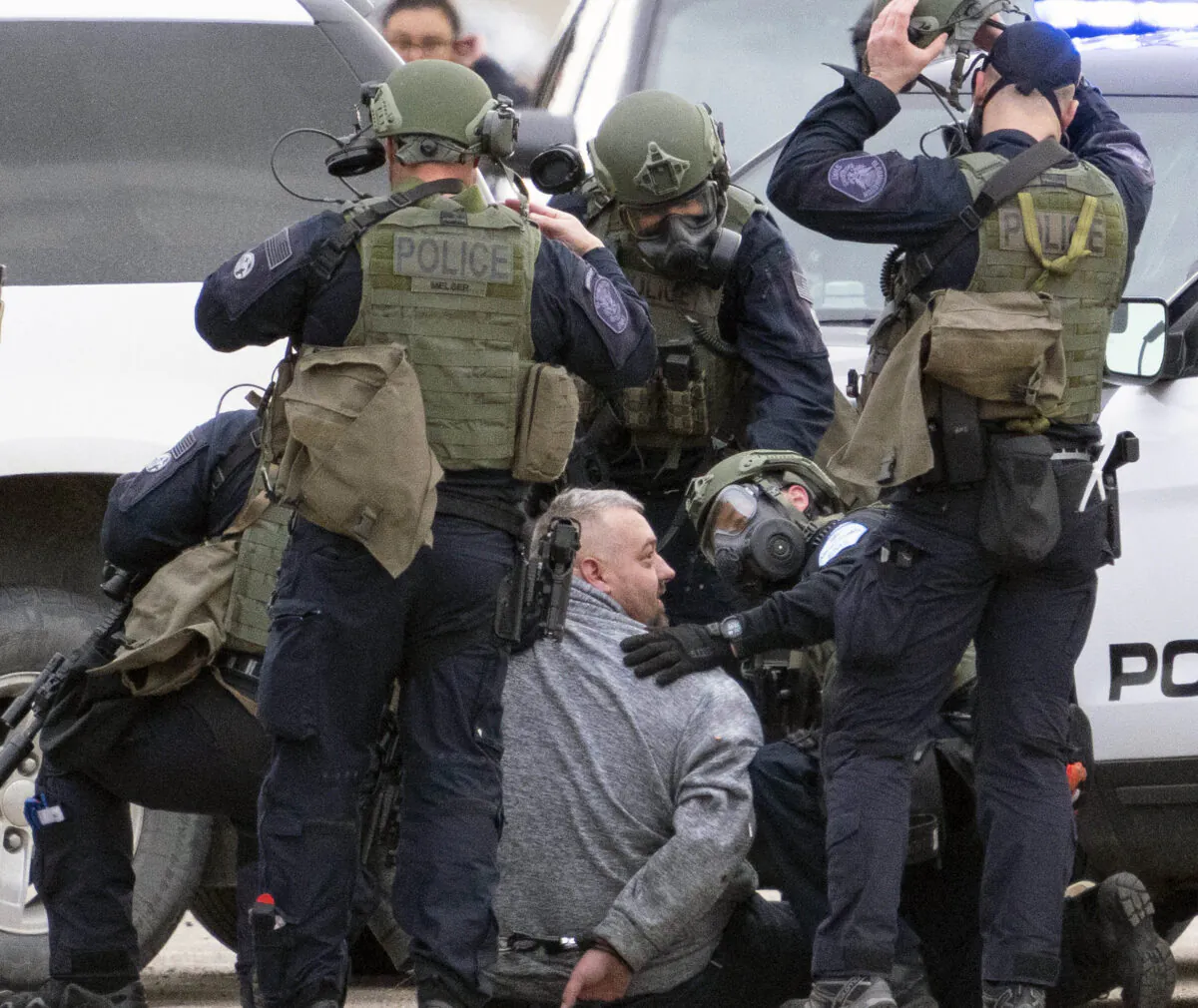 Police restrain and handcuff a man who was shot with non-lethal projectiles after exiting his vehicle at the conclusion of a standoff in the North parking lot of the Mall of America, in Bloomington, Minn., on April 21, 2023. (Alex Kormann/Star Tribune via AP)
