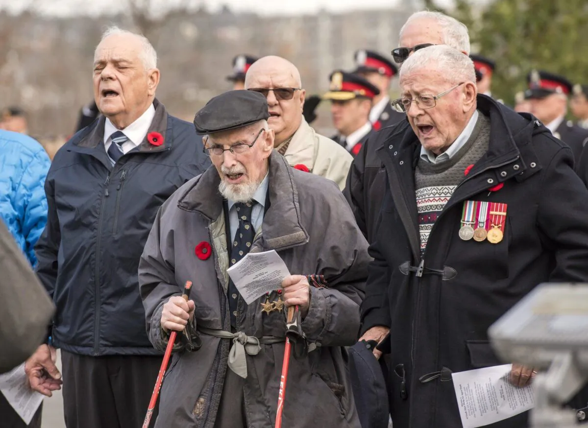 100-year-old Second World War veteran Angus Hamilton, centre, and Rev. Bob Jones, right, sing O Canada as part of the provincial Remembrance Day ceremony in Fredericton, Nov. 11, 2022. (The Canadian Press/Stephen MacGillivray)
