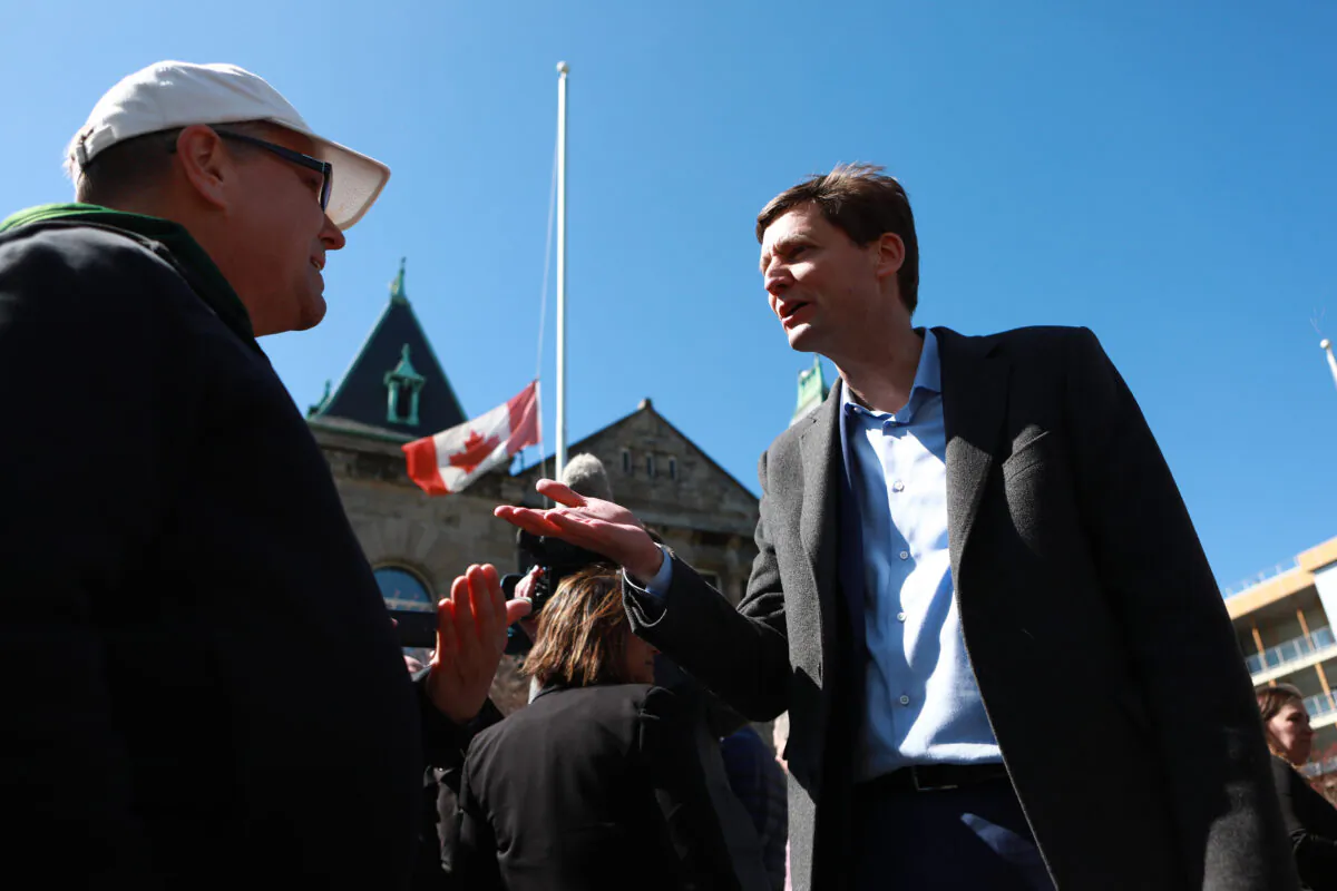 Nanaimo resident Peter Louhimo asks B.C. Premier David Eby about catch-and-release offenders following the announcement about new hubs that will target violent crime, following a press conference in front of the Provincial Court of British Columbia in Nanaimo, B.C., on April 12, 2023. (The Canadian Press/Chad Hipolito)