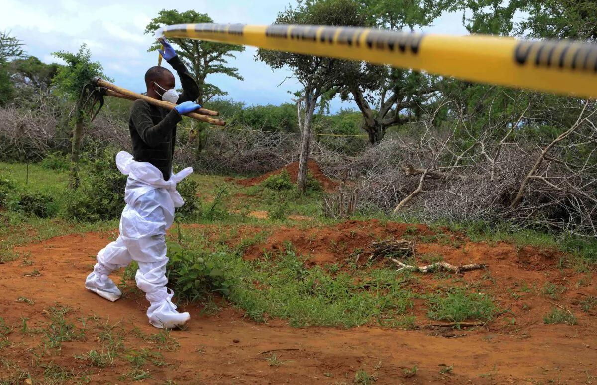 A homicide detective crosses the cordon line to exhume bodies of suspected members of a Christian cult named as Good News International Church, in Shakahola forest of Kilifi county, Kenya, on April 22, 2023. (Stringer/Reuters)